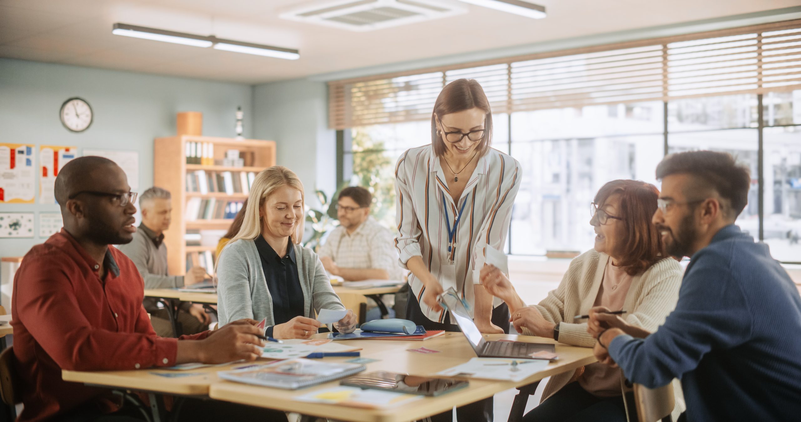 Grown-Up Men and Women Working in Groups for an Assignment in Specialty Development Center. Adult Classmates Working on a Team Assignment, Young Female Teacher Explaining the Exercise Objectives