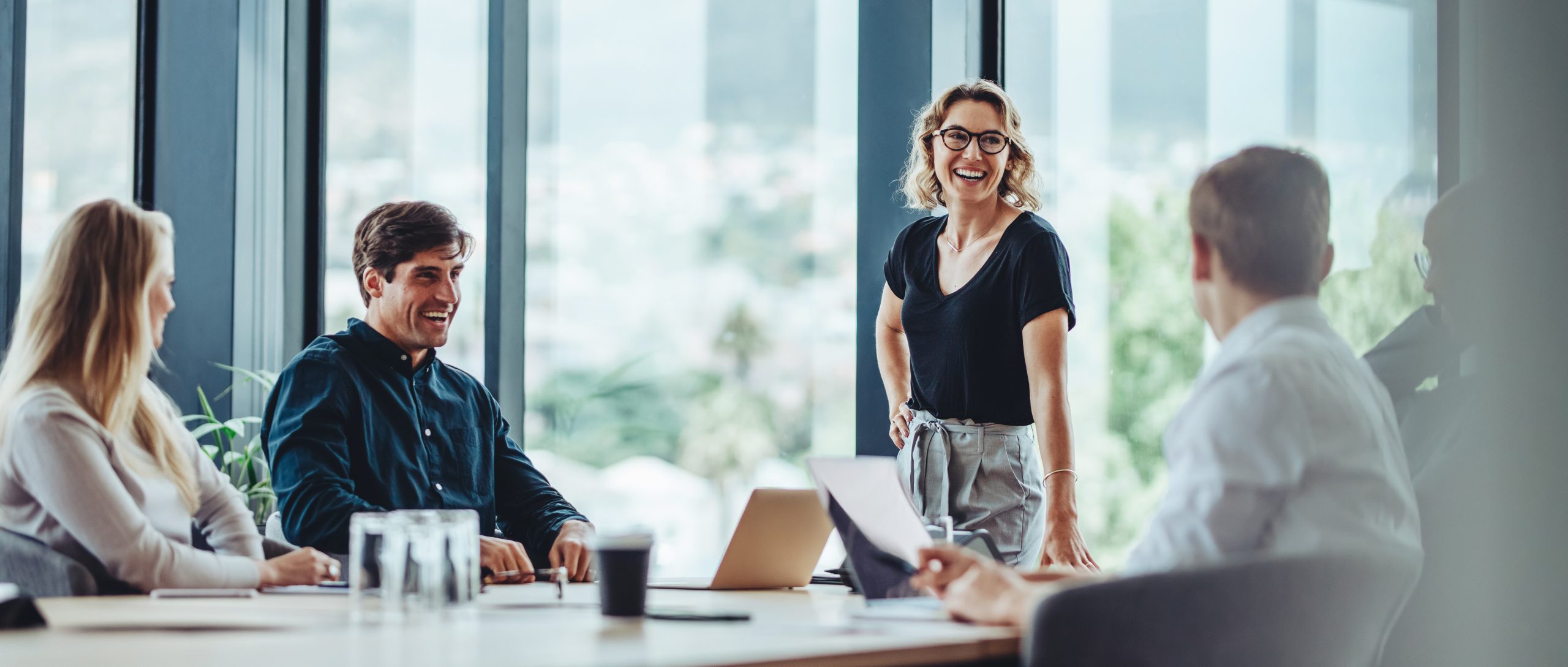 Group of colleagues engaging in a discussion during a business meeting in a conference room. Happy business people, men and women, collaborating and working towards their shared goals.