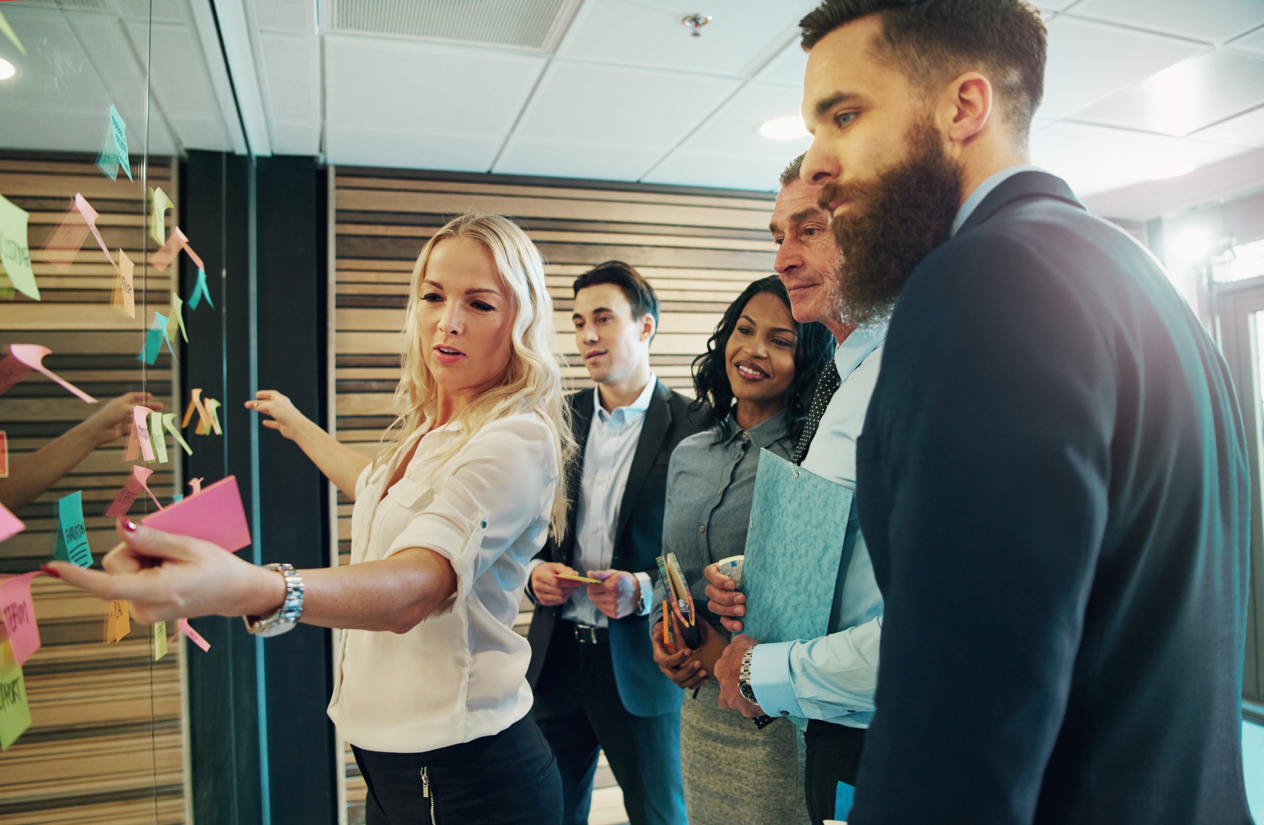 Creative group of business people looking at sticky notes on glass partition in office