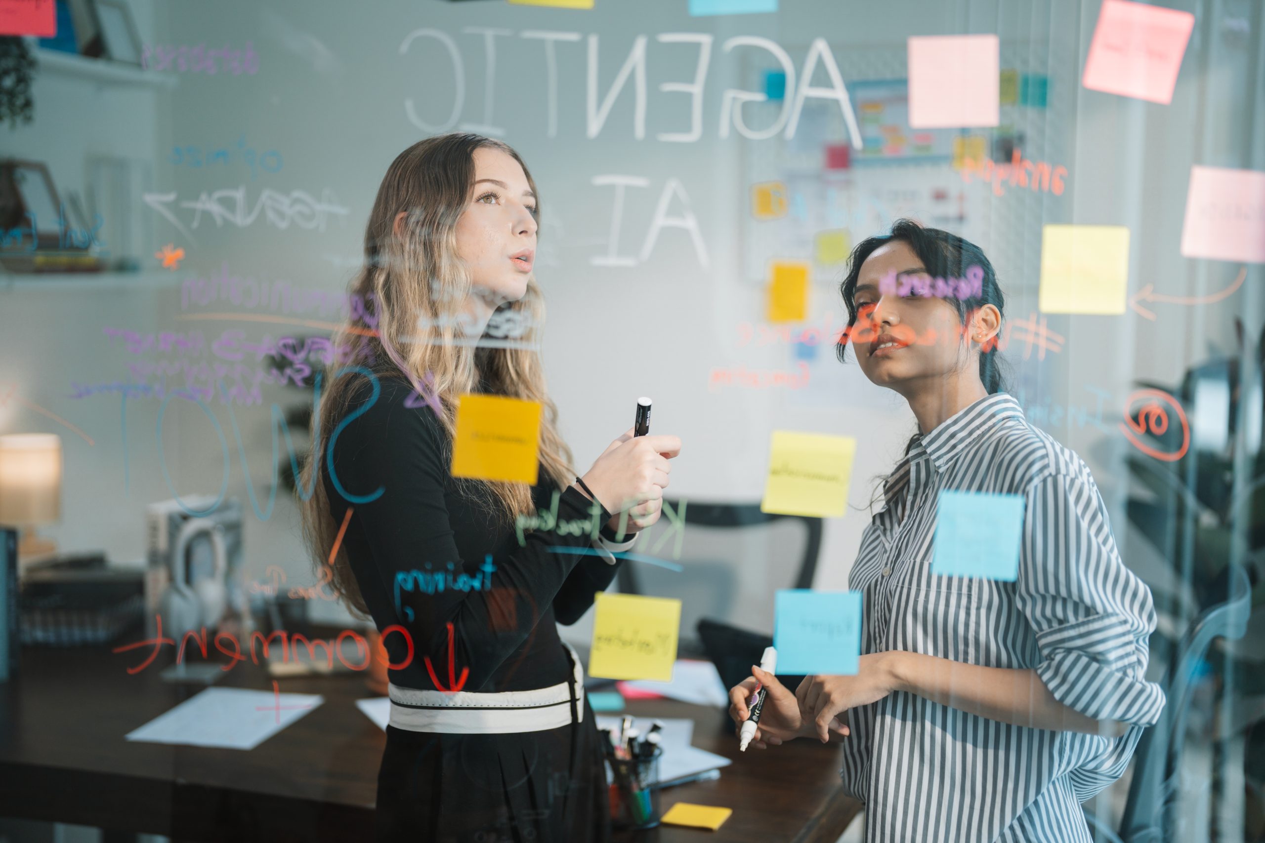 Colleagues Brainstorming Ideas with Sticky Notes on Glass Board